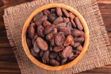 Aromatik ham kakao çekirdekleri çuval bezi peçete ile dolu ahşap arka plan üzerinde top. Üstten görünüm. Kopya alanı