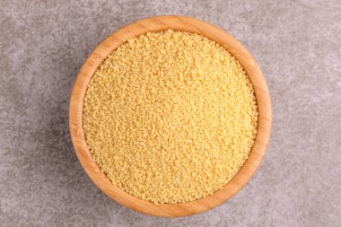 Ham kuskus tahıl gri mermer zemin üzerine ahşap kase. Uzay kopyalayın. Üstten görünüm