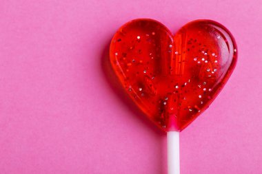 Parlak pembe bir arka plan üzerinde kalp şeklinde kırmızı tatlı lezzetli lolipop. St. Valentine's day. Kopya alanı