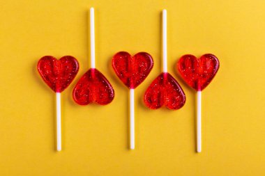 Beş kırmızı tatlı lezzetli lolipop parlak sarı zemin üzerinde kalp şeklinde. St. Valentine's day. Kopya alanı