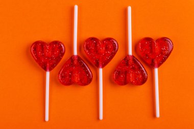 Beş kırmızı tatlı lezzetli lolipop parlak turuncu zemin üzerinde kalp şeklinde. St. Valentine's day. Kopya alanı