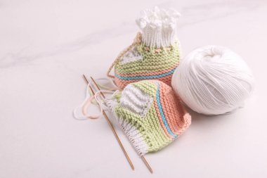 İplik ve beyaz mermer zemin üzerine iğne ile bebek patiği örme. Sıcak el yapımı bebek için çorap