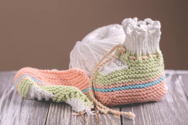 Örgü bebek patik iplik ve gri rustik ahşap arka plan üzerinde iğne ile. Sıcak el yapımı bebek için çorap