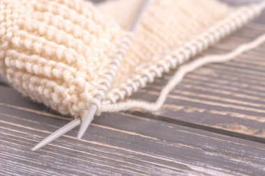 Gri rustik ahşap zemin üzerine yün iplik sıcak örgü deseni. Beggining yeni el yapımı örgü atkı veya diğer kış giysileri