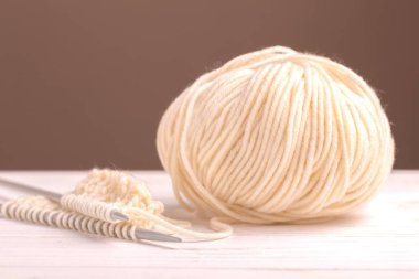 Sıcak beyaz rustik ahşap zemin üzerine yün iplik örgü deseni. Beggining yeni el yapımı örgü atkı veya diğer kış giysileri