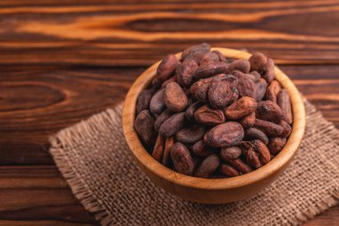 Aromatik ham kakao çekirdekleri çuval bezi peçete ile dolu ahşap arka plan üzerinde top. Yatay görünüm. Kopya alanı