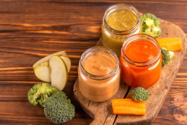 Varyasyon vintage kesme tahtası üzerinde malzemelerle cam kavanoz bebek maması pureed. Ahşap arka plan. Kopya alanı