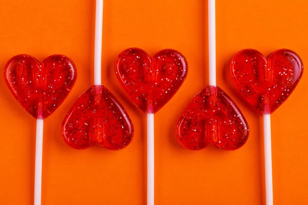 Cinco Pirulitos Saborosos Doces Vermelhos Forma Coração Fundo Laranja Brilhante — Fotografia de Stock