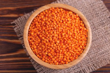 Rustik ahşap zemin üzerine çuval bezi peçete ahşap kase çiğ kırmızı mercimek