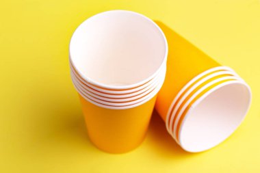 Geri dönüşüm kağıt bardak içmeye parlak sarı zemin üzerine. Uzay kopyalayın. Parti ve geri dönüşüm kavramı