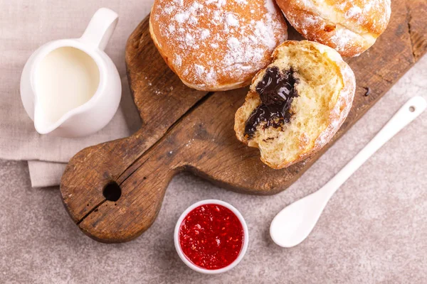 Lezzetli tatlı şekerli çikolata lokmalar frambuaz reçeli ve eski ahşap rustik kesme tahtası üzerinde süt ile. Geleneksel Yahudi tatlı Hanukkah çanak. Gri mermer zemin