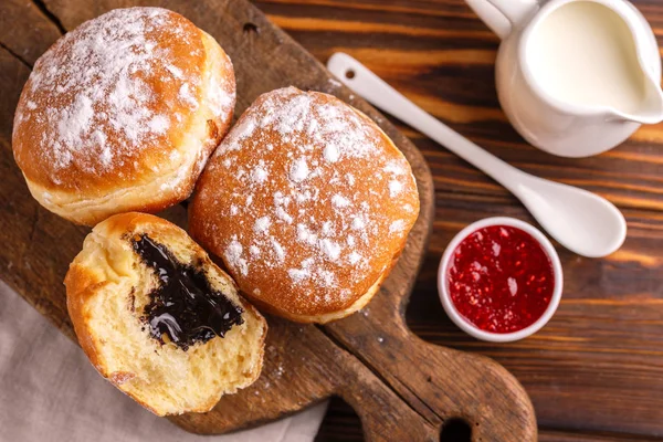 Lezzetli tatlı şekerli çikolata lokmalar frambuaz reçeli ve eski ahşap rustik kesme tahtası üzerinde süt ile. Geleneksel Yahudi tatlı Hanukkah çanak. Ahşap arka plan