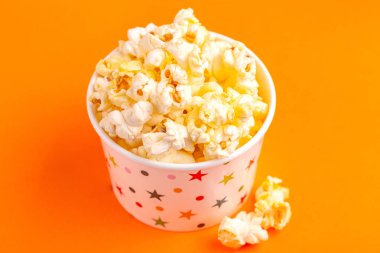 Kağıt bardak üzerinde parlak turuncu backgraund lezzetli tuzlu Mısır. Eğlence film izlerken. Sinema aperatifler. Kopya alanı