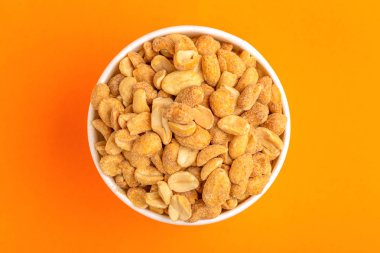 Kağıt bardak parlak turuncu zemin üzerine kavrulmuş fıstık. Film aperatifler. Kopya alanı