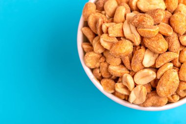 Kağıt bardak parlak mavi zemin üzerine kavrulmuş fıstık. Film aperatifler. Kopya alanı