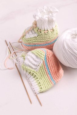 İplik ve beyaz mermer zemin üzerine iğne ile bebek patiği örme. Sıcak el yapımı bebek için çorap