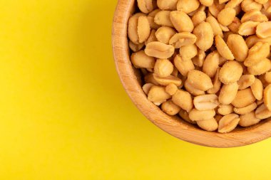 Ahşap kase parlak sarı zemin üzerine kavrulmuş fıstık. Film aperatifler. Kopya alanı