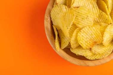 Çıtır patates cipsi ahşap kase parlak turuncu zemin üzerine oluklu. Abur cubur. Kopya alanı