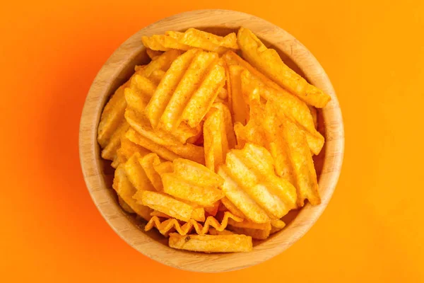 Crispy Gegolfd Potato Chips Houten Kom Helder Oranje Achtergrond Junkfood — Stockfoto
