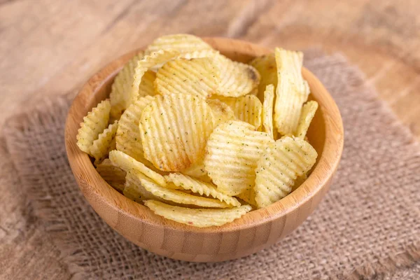 Çıtır patates cipsi çuval bezi peçete üzerinde ahşap kase oluklu. Ahşap arka plan. Abur cubur. Kopya alanı