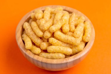 Parlak renkli arka plan üzerinde ahşap kase gevrek Mısır yapışır. Film izlemek için abur cubur. Kopya alanı