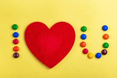 İtiraf yardımı ile sırlı renkli çikolata şekerleme seviyorum ve sarı zemin üzerine kalp hissettim. Sevgililer günü. Düz yatıyordu