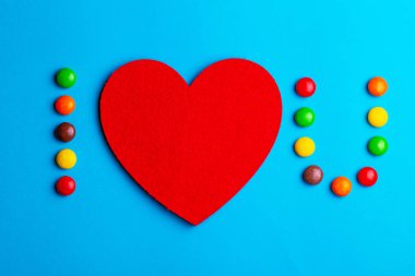 Yardım itirafla sırlı renkli çikolata şekerleme, sevgi ve kalp mavi arka plan üzerinde hissetti. Sevgililer günü. Düz yatıyordu