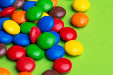 Sırlı renkli çikolata şekerleme parlak yeşil arka plan üzerinde toplanmış bulunuyoruz. Yatay görünüm. Kopya alanı