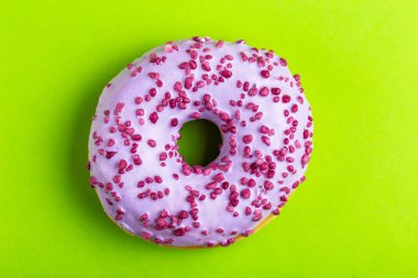 Parlak yeşil zemin üzerine serpin ile lezzetli leylak çörek. Sağlıksız, ama lezzetli tatlılar. Uzay kopyalayın. Üstten görünüm