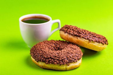 Serpin ve parlak yeşil zemin üzerine kahve ile iki lezzetli çikolatalı çörek. Sağlıksız, ama lezzetli tatlılar. Uzay kopyalayın. Yatay görünüm