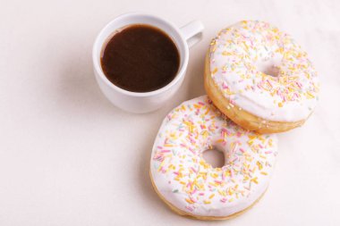 Bir kahve ışık mermer zemin üzerine serpin ve ile iki lezzetli vanilyalı donut. Sağlıksız, ama lezzetli tatlılar. Uzay kopyalayın. Yatay görünüm