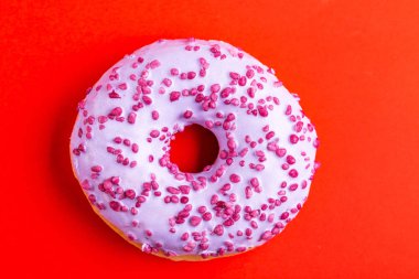 Lezzetli leylak çörek ile parlak kırmızı zemin üzerine serpin. Sağlıksız, ama lezzetli tatlılar. Uzay kopyalayın. Üstten görünüm