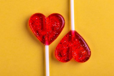 İki kırmızı tatlı lezzetli lolipop parlak sarı zemin üzerinde kalp şeklinde. St. Valentine's day. Kopya alanı
