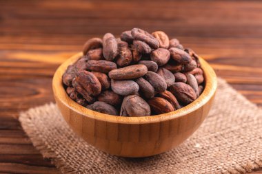 Aromatik ham kakao çekirdekleri çuval bezi peçete ile dolu ahşap arka plan üzerinde top. Yatay görünüm. Kopya alanı