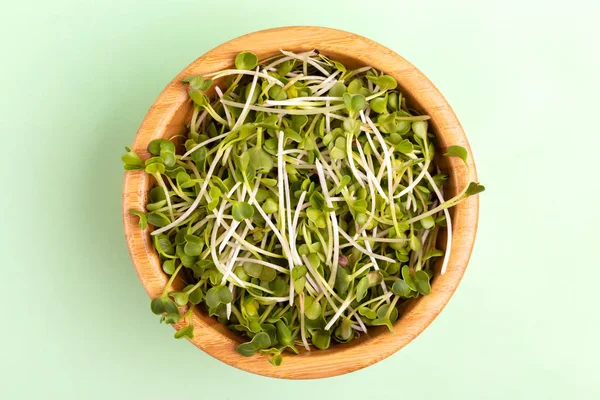 Açık yeşil arka planı üzerinde ahşap kase germinated turp lahanası. Sebze Salatalar, Çorbalar, tabak ve sandviç süsleme için yeşil. Kopya alanı