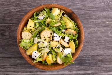 Frisee, mango, beyaz peynir ve ahşap kase gevrek kruton lezzetli salata. Ahşap arka plan. Kopya alanı