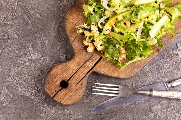 Frisee, avokado, kaju fıstığı ve siyah susam ile lezzetli salata vintage kesme tahtası üzerinde servis. Karanlık beton arka plan. Uzay kopyalayın. Üstten görünüm