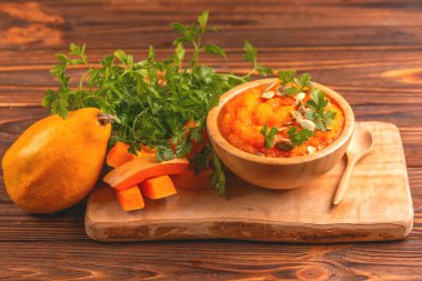 Bright lezzetli balkabağı çorbası kesme tahtası üzerinde malzemelerle ahşap kase ezilmiş. Sağlıklı gıda kavramı. Rustik ahşap arka plan. Yatay görünüm. Kopya alanı