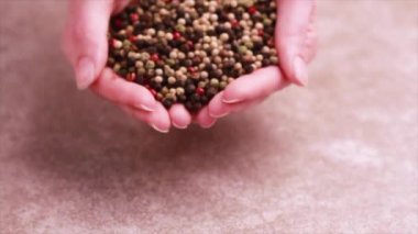 Kırmızı, siyah, beyaz ve yeşil biber karışımı gri mermer zemin üzerine kadının elinden düştü. Yatay görünüm