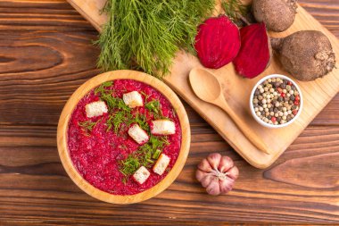 Bright lezzetli kırmızı pancar çorbası kesme tahtası üzerinde malzemelerle ahşap kase ezilmiş. Sağlıklı gıda kavramı. Rustik ahşap arka plan. Üstten görünüm. Kopya alanı