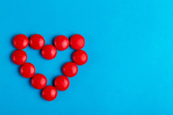 Pequenos Doces Vermelhos Chocolate Envidraçado Moldados Coração Fundo Azul Brilhante — Fotografia de Stock