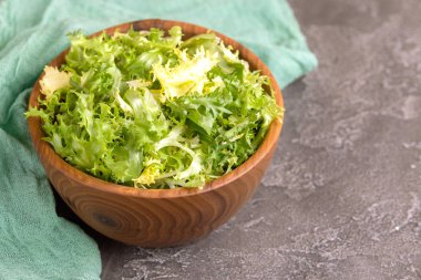 Ahşap kase taze frisee salata. Sağlıklı gıda. Karanlık beton arka plan. Kopya alanı