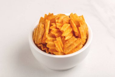 Çıtır patates cipsi ışık mermer zemin üzerine beyaz kase oluklu. Abur cubur. Kopya alanı