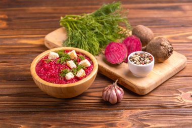 Bright lezzetli kırmızı pancar çorbası kesme tahtası üzerinde malzemelerle ahşap kase ezilmiş. Sağlıklı gıda kavramı. Rustik ahşap arka plan. Yatay görünüm. Kopya alanı