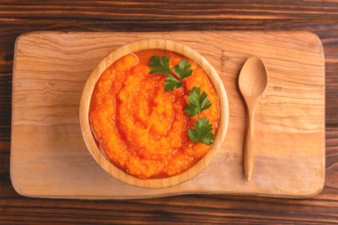 Bright lezzetli pureed havuç çorbası kesme tahtası üzerinde ahşap kase. Sağlıklı gıda kavramı. Rustik ahşap arka plan. Üstten görünüm. Kopya alanı