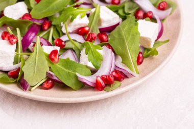 Ispanak, roka, kırmızı soğan ve plaka ışık mermer zemin üzerine nar ile sağlıklı salata. Kopya alanı