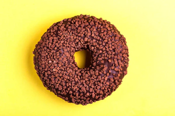 Lezzetli çikolatalı çörek ile parlak sarı zemin üzerine serpin. Sağlıksız, ama lezzetli tatlılar. Uzay kopyalayın. Üstten görünüm