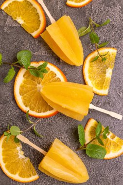 Gri beton zemin üzerine olgun turuncu ve taze nane ile ev yapımı turuncu buzlu şeker. Sağlıklı tatlılar. Laktoz ücretsiz dondurma.