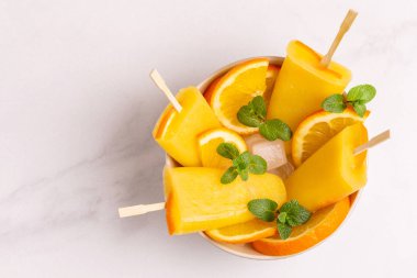 Işık mermer zemin üzerine olgun turuncu ve taze nane ile ev yapımı turuncu buzlu şeker. Sağlıklı tatlılar. Laktoz ücretsiz dondurma.