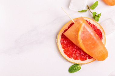 Ev yapımı greyfurt olgun greyfurt dilim ve ışık mermer zemin üzerine taze nane ile buzlu şeker. Sağlıklı tatlılar. Laktoz ücretsiz dondurma.